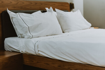 White pillows and sheets in a bedroom in a beauty salon. Close. Large double bed for comfortable sleep and relaxation. Modern comfortable white cotton bed linen.