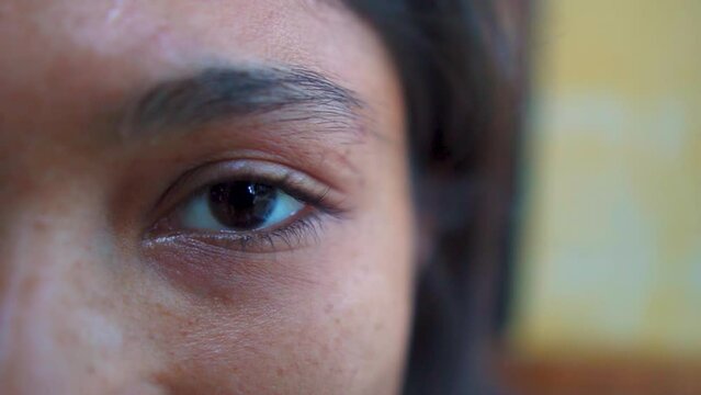 Extreme close up of Indian Woman opening beautiful eye with blue iris. Attractive girl, a young female model looking at camera. Slow-motion, macro shot