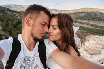A selfie shot of a young couple in love, a man and a woman, at a height on a hill.