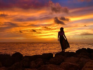 Chica posando en rocas frente al mar con cielo en atardecer en cartagena de indias