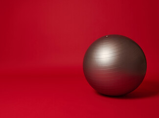 Silver fit ball on a bright red background with copy space for advertising text. Sport, fitness, sports equipment concept