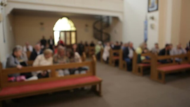 Parishioners sit in the church on the benches. Blurred image.