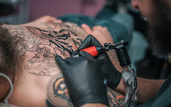 Professional tattooist makes a tattoo on the skin in a workshop studio