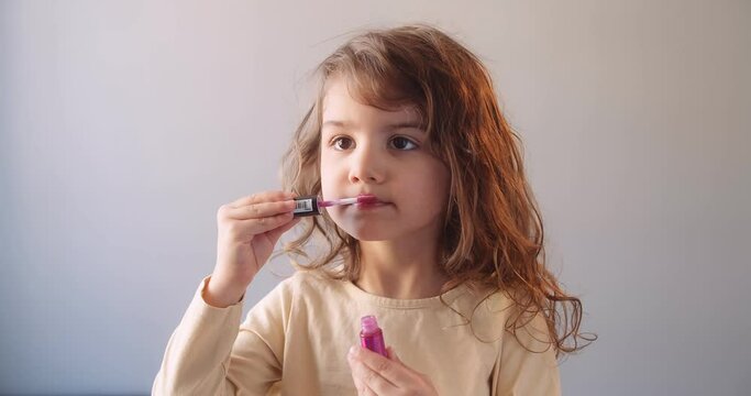 Cute toddler girl applying makeup by herself. Shot in 4K on a cinema camera.