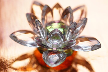 Crystal lotus on orange table with light reflection. Svadhisthana chakra symbol.