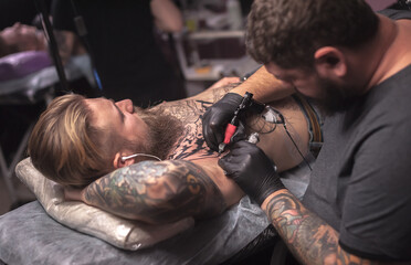 Fototapeta na wymiar Professional tattooist making a tattoo in tattoo studio