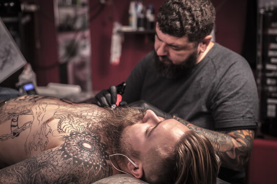 Professional tattooer makes tattoo in tattoo parlor