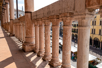 Naklejka premium The scenic view on Piazza delle Erbe from the loggia which is the external balcony of Palazzo della Ragione in Padua, Veneto, Italy, Europe. Light beams on beautiful colonnade with column architecture