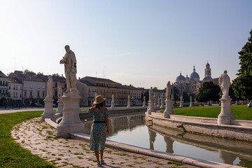 Woman in a dress and hat walking at Prato della Valle, square in the city of Padua, Veneto, Italy,...