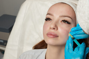 Syringe with a patient's blood plasma in a cosmetologist's hand for a plasmolifting of a woman's...