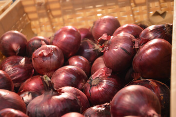 Red onions are on display in abundance on the supermarket counter. Fresh vegetables, harvesting. Vegetarian food.