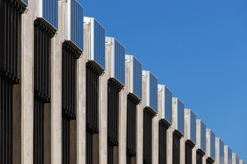 Part of the construction of a building made of glass, iron, metal, concrete, in perspective against the sky