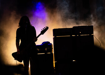silhouette of a person playing a bass guitar