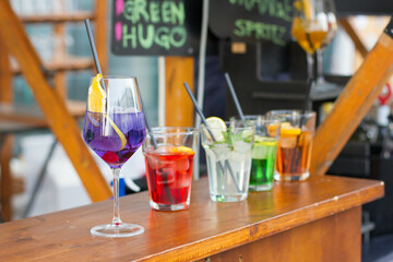 A line of colorful cocktails on a wooden table.