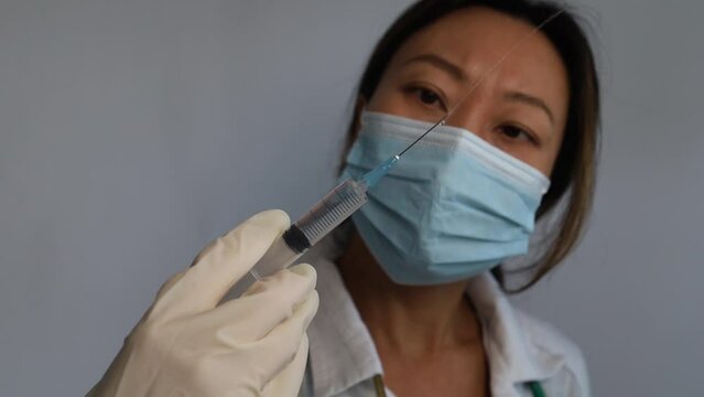 A doctor or scientist in the COVID-19 medical vaccine research and development laboratory holds a syringe with a liquid vaccine to study and analyze antibody samples for the patient.