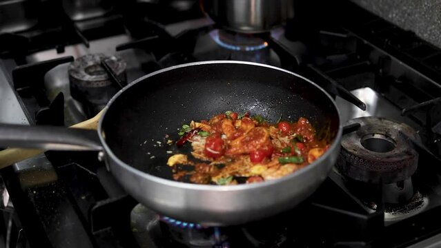 chef cooking black pasta with shrimps,garlic,chili,tomato,basil and tomato sauce