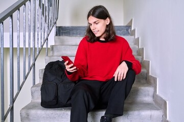 Young male sitting on stairs using smartphone