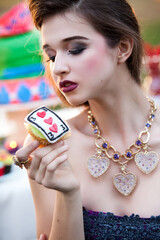 High Fashion Beauty Model with Makeup wearing Jewelry Holding Whimsical Alice in Wonderland Inspired Cake