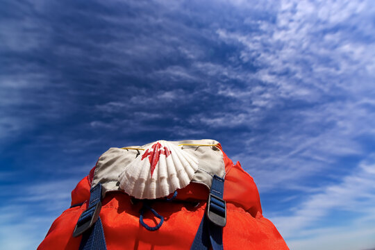 Way of St James , Camino de Santiago ,scallop shell on backpack with blue sky and clouds  to Compostela , Galicia, Spain