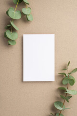 Business concept. Top view vertical photo of paper sheet and eucalyptus sprigs on beige background with empty space