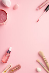 Obraz na płótnie Canvas Top view vertical photo of beauty blenders pink eye patches with special spoon lip gloss glass dropper bottle makeup brushes and two stylish hairpins on pastel pink background with blank space