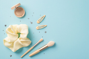 Make up concept. Top view photo of stylish scrunchy makeup brushes hairpins eyeshadow and shiny star shaped confetti on isolated pastel blue background with copyspace