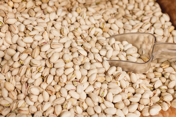 Salted pistachios nuts in shell with shovel on counter in organic super market.