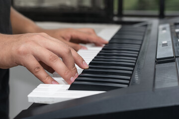 young latin man, playing musical piano notes on a synthesizer, boy practicing high notes. detail...