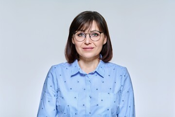 Portrait of business mature woman looking at camera on light studio background