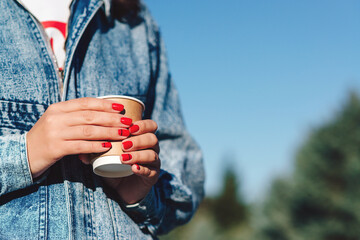 Female hand with coffee take away. Woman holding cup in hands. Drinking take away coffee.