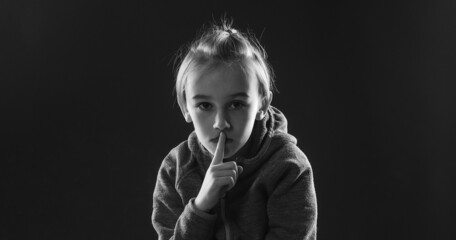 Sad afraid child sitting quiet in dark. Young boy suffering from anxiety. Stressed boy over black background.