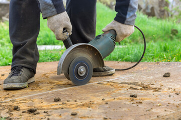 Construction worker sawing with saw disk cutter the metal sheet