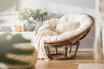 Rattan papasan chair with a beige pillow in a modern luminous apartment 