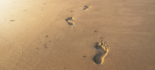 Summer Vacation background - Footprints on tropical beach at sunset time