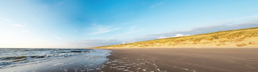 Sand dune with wild grass and beach in Noordwijk on the North Sea in Holland Netherlands - Panorama sea landscape with blue sky and clouds