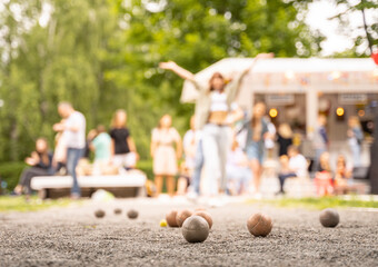 Friends playing petanque girl  celebrate victory above summer city cafe outdoor activity game