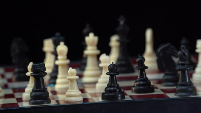 Cess board with figures on a black background, Rotating camera. Sport match. Business concept. White against black. Competition.