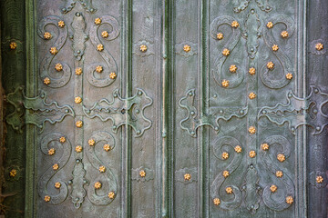 Closeup of acient green forged doors with golden stars, tectured background. Dominican church in Lviv