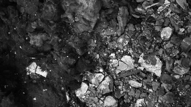 Close up top view bw 4k video footage of terrible real burnt to ash debris and remains of civil housing after bombing during war of Russia  against Ukraine aircraft attack. Abstract video background
