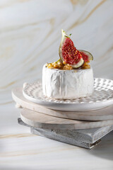 Brie cheese with figs, walnuts, thyme, honey on a light background. Breakfast or brunch option