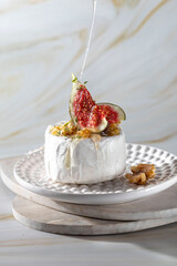 Brie cheese with figs, walnuts, thyme, honey on a light background. Breakfast or brunch option