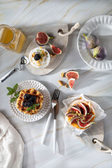 Camembert cheese with figs, walnuts, thyme and honey on a white marble table .French dessert