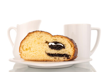 One slice of homemade poppy seed roll on a ceramic saucer with a white cup and a milk jug, close-up, isolated on a white background.