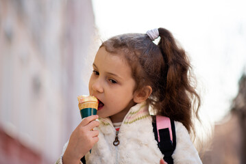 A cute little girl eats ice cream outside. Takeaway. Happiness. Childhood. The concept of delicious food.