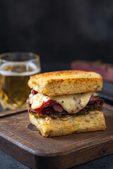 Sandwich with beef pastrami on wooden board