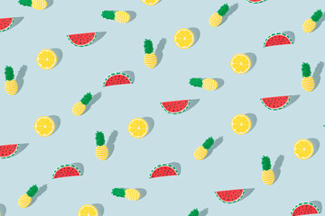 Summer fruit pattern made of lemon, pineapple, and watermelon on a pastel blue background. Minimal summer fruit background concept.