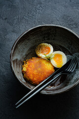 Delicious fried hot potato croquet with soft-boiled egg close-up in a bowl on the table