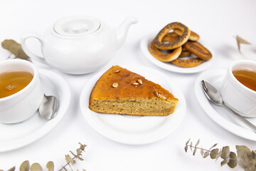 A piece of cake on a saucer with a cup for tea or coffee and a kettle