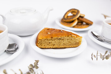 A piece of cake on a saucer with a cup for tea or coffee and a kettle