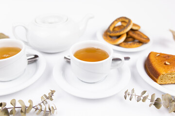 Obraz na płótnie Canvas white tea set with teapot tea and saucers and pie for breakfast